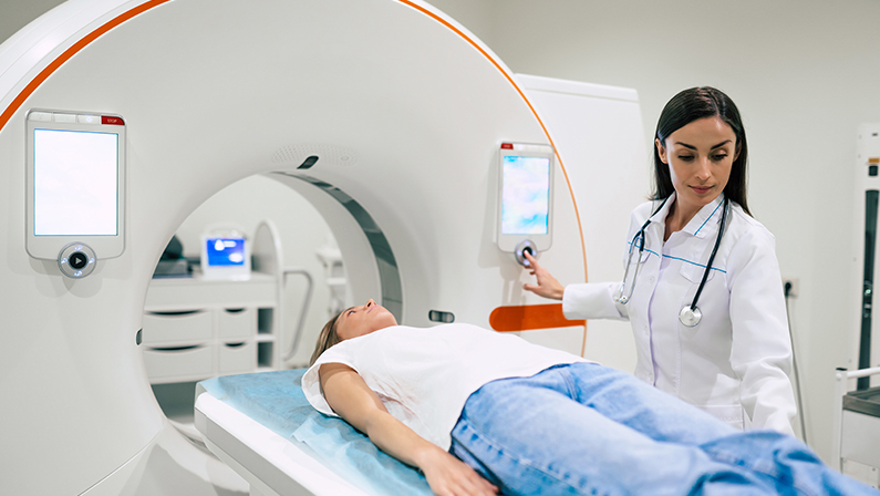 Professional Doctor Radiologist In Medical Laboratory Controls magnetic resonance imaging or computed tomography or PET Scan with Female Patient Undergoing Procedure.