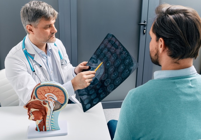 Doctor explaining to male patient results of MRI scan of his brain. Diagnosis of diseases and head injuries