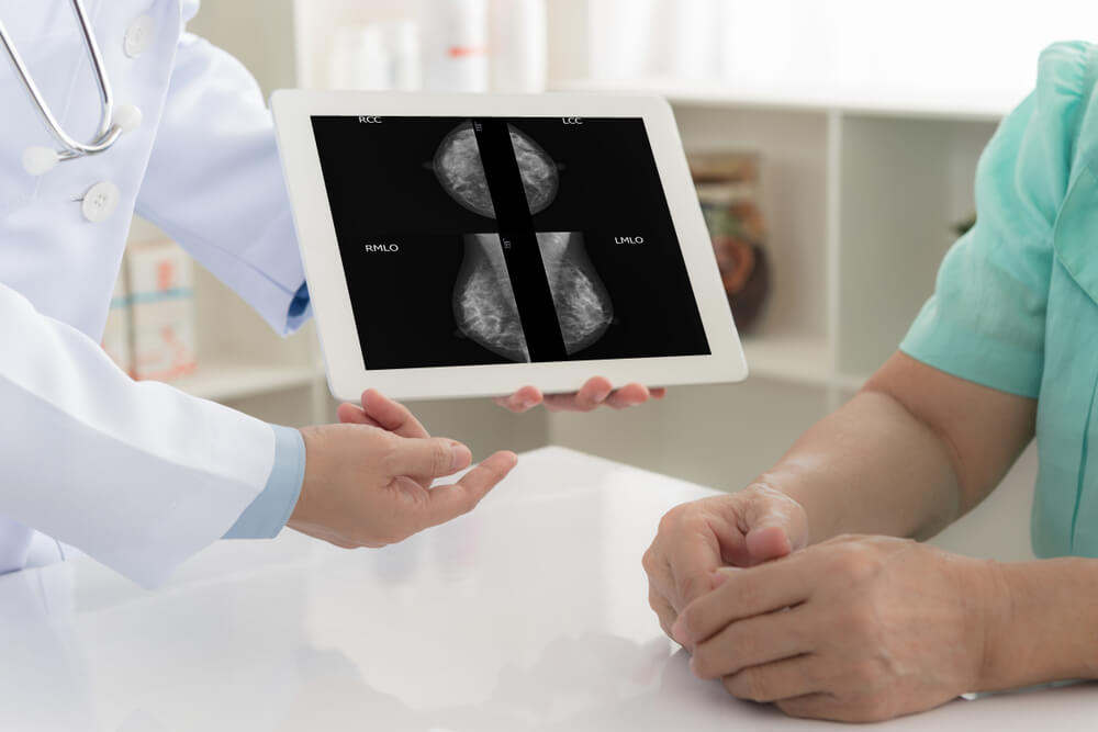 breast mammography concept. doctor explaining results of breast checkup by mammogram on digital tablet screen to patient.
