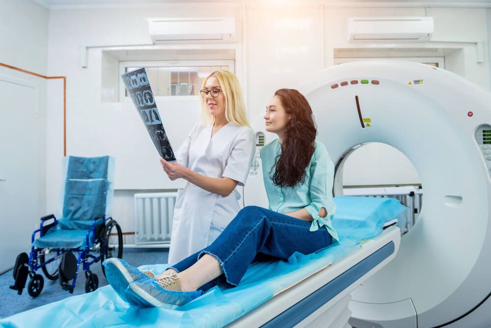 Radiologist with a female patient examining a CT scan
