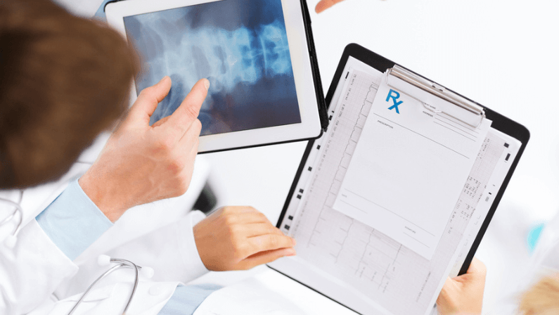 Healthcare, hospital and medical concept - group of doctors looking at x-ray on tablet pc