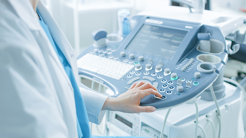 In the Hospital, Obstetrician Pushes Buttons on a Control Panel Before Starting Ultrasound / Sonogram Procedure.