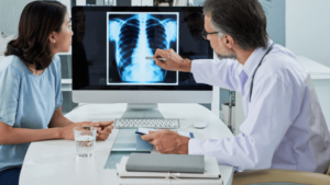 Doctor explaining lungs x-ray on computer screen to young patient
