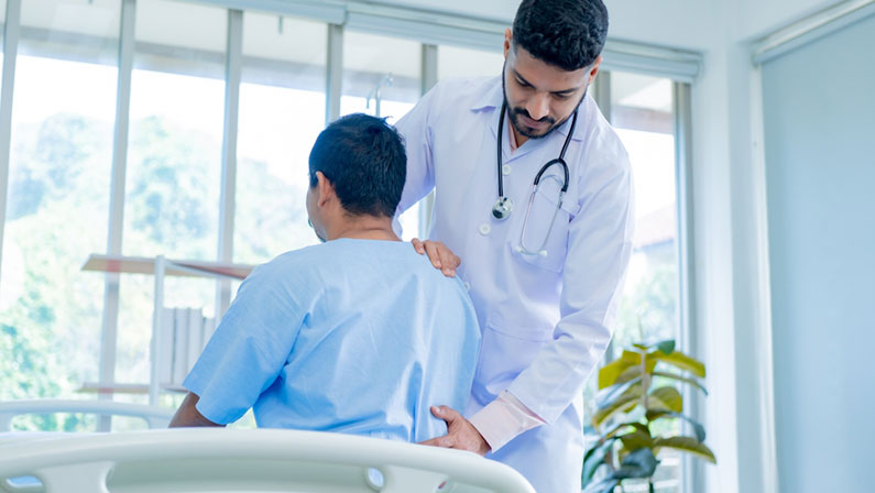 Doctor physiotherapist treating lower back pain patient after while giving exercising treatment on stretching in the hospital, Rehabilitation physiotherapy concept.