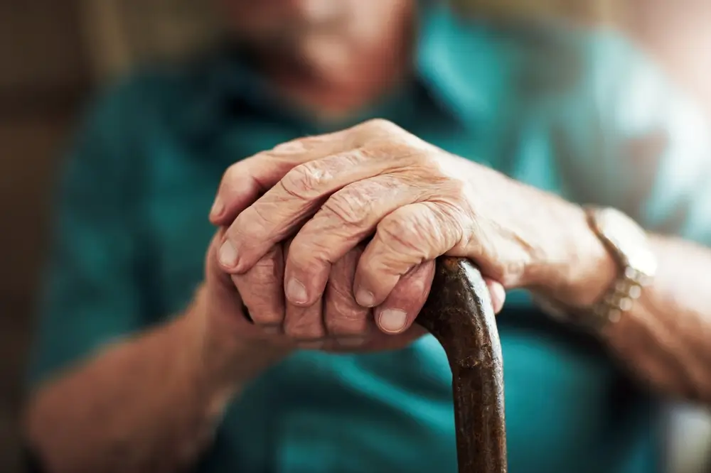 Senior man, hands and support with cane for old age, osteoporosis or care in retirement home. 