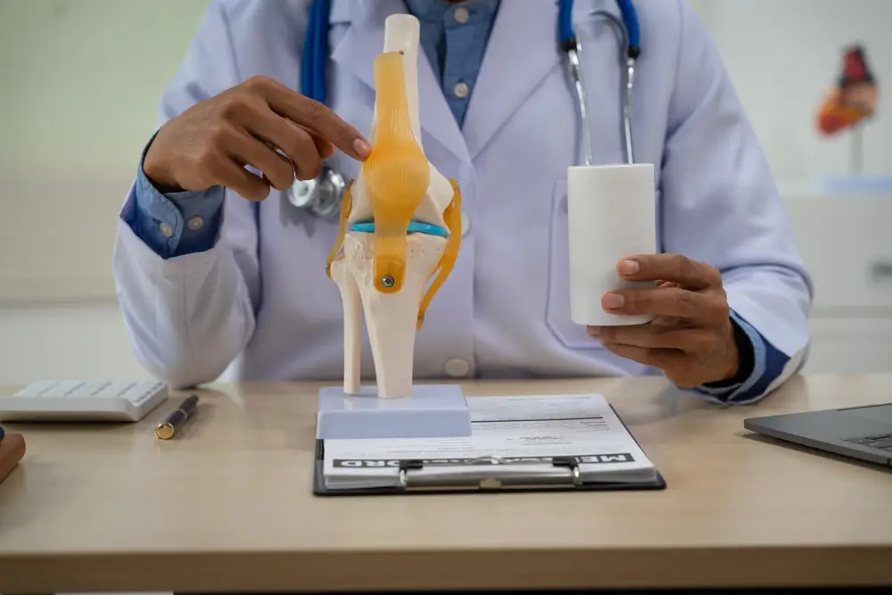 A male doctor in leather works at the table in the bone disease clinic, addressing issues such as cervical spine disease, osteoporosis, herniated discs, and more with expert care.
