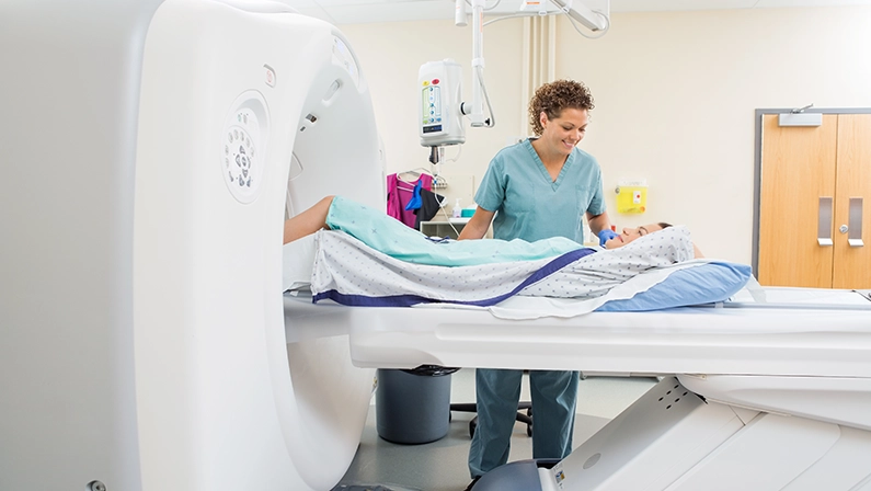 Female nurse looking at patient undergoing CT scan test in examination room