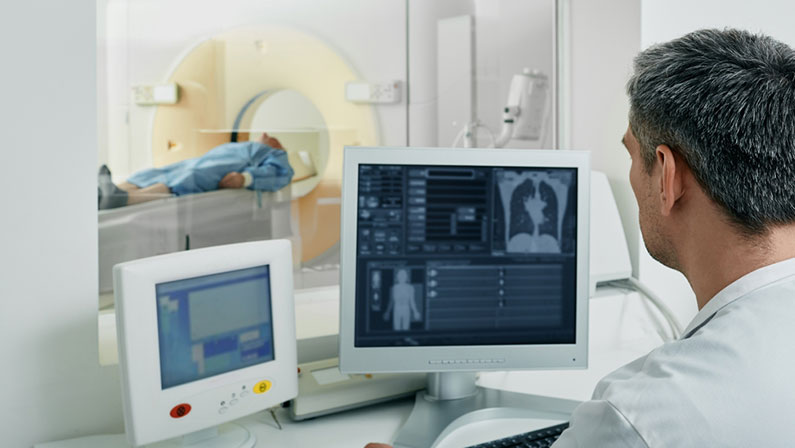 Doctor radiologist running CT scan for patient's body lungs from control room. Computed Tomography